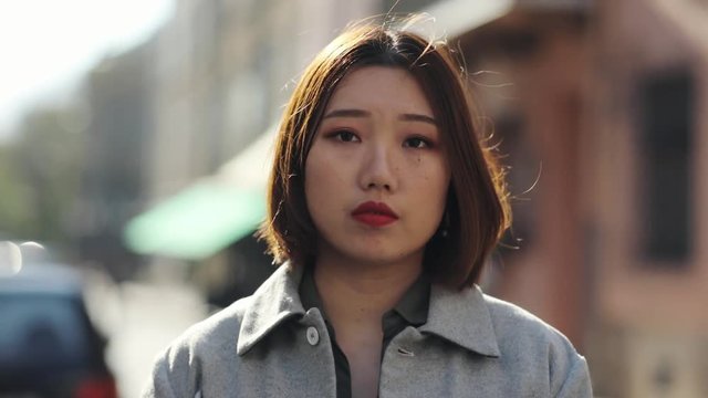 Close up serious face Asian woman look at camera sad outdoor girl eye asian beautiful beauty chinese expression fashion japanese portrait young attractive cute gorgeous hair slow motion