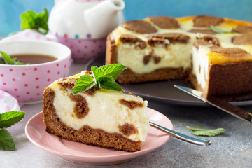 The concept of breakfast or relaxation. Chocolate New York cheesecake and mint tea cup on concrete background.