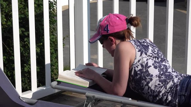 A woman reads a book outside in the sunshine
