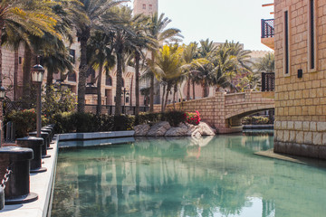 Madinat Jumeirah is an area called Dubai Venice. Channels with water around which are houses and palm trees.