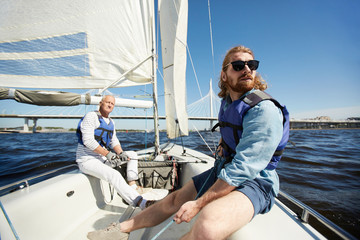 Young and senior active men floating on yacht on hot summer weekend - obrazy, fototapety, plakaty