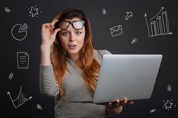 Clever woman. Clever experienced economist standing with a laptop in her hands and touching the...