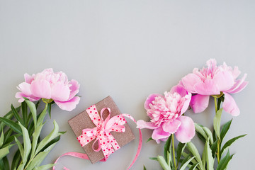 Bouquet of pink peonies and gift box decorated with ribbon, top view, copy space