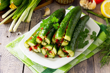 Korean traditional food Kimchi (Cucumber). Marinated cucumbers with vegetable filling (sweet pepper, garlic, onion, greens, tomato paste) on the kitchen wooden table.