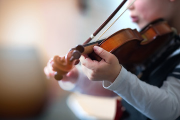 Child playing the violin in  room
