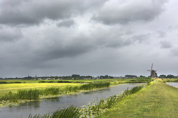 Scenic view with water, grass, thunderclouds and windmill in the environment of Zwammerdam. the Netherlands. Zwammerdam is a  village in the Green Heart, Groene Hart in the province South Holland.