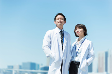 遠くを見つめる白衣の男女（医者と科学者のイメージ）