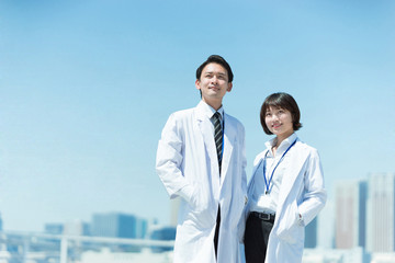 遠くを見つめる白衣の男女（医者と科学者のイメージ）