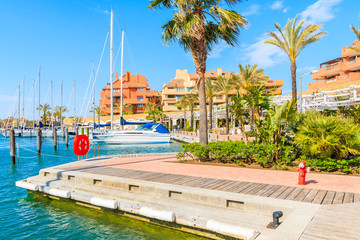 Pier for sailing boats in beautiful Sotogrande marina with colorful houses and palm trees, Costa del Sol, Spain