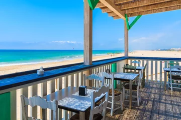 Photo sur Plexiglas Plage de Bolonia, Tarifa, Espagne TARIFA BEACH, SPAIN - MAY 8, 2018: Restaurant tables on terrace on sandy beach on Costa de la Luz. Spain is second most visited by tourists country in Europe.