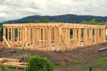 Fototapeta na wymiar Wooden construction of an unfinished house. Skeleton of a building made of beams.