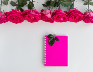 розовый блокнот на белом фоне, украшенном розами