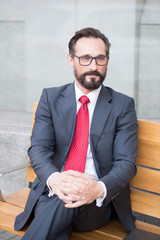 Middle-aged businessman taking a relaxing break on bench. City Life Series of business persons....