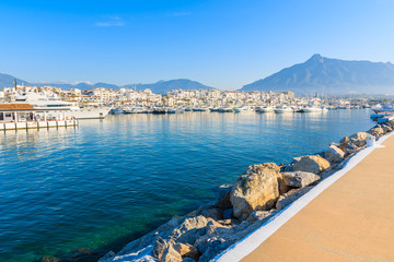 Obraz premium View of Puerto Banus marina with boats and white houses in Marbella town at sunrise, Costa del Sol, Spain