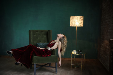 Beautiful blonde in black velvet dress on aristocratic apartment background.