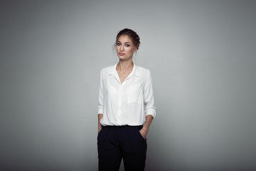 Interested businesswoman with trendy makeup posing on gray background in studio. Indoor photo of...