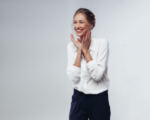 beautiful businesswoman in white blouse and black pants fun laughing and rejoicing at victory against white background in studio