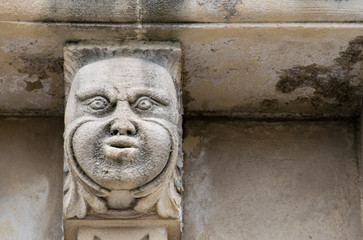 Closeup view of mascarons with  funny faces under the balcony of a baroque palace in the province of Syracuse, Sicily