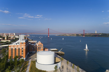Aerial view of the city of Lisbon with sail boats on the Tagus River and the 25 of April Bridge on the background; Concept for travel in Portugal and visit Lisbon