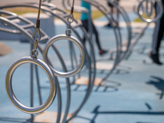 Steel gymnastic rings suspended low at an outdoor gym with copy space to right