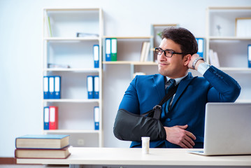 Businessman with broken arm working in office