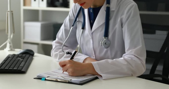 Cropped image of female doctor filling documents .