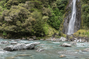 Naklejka na ściany i meble Thunder Creek Falls in Mt Aspiring National Park, with the Haast River in the foreground. Mt Aspiring National Park, West Coast, New Zealand.