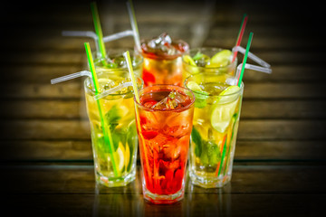 Glasses of cocktails on bar background