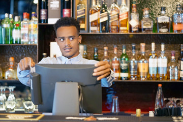 Registration male of bartender employee of a new order by a cash register. The barman pays the order with a credit card. Service concept. Close-up.