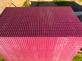 A house with a red roof made of corrugated metal sheets. Roof from corrugated metal profile. Metal tiles