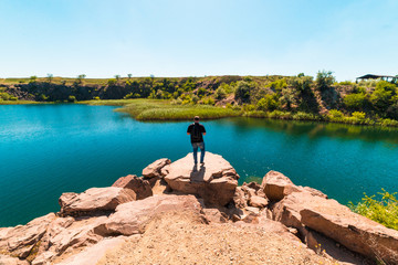 guy tourist on a cliff face looking at a pond, tourism, vacation, travel, summer vacation
