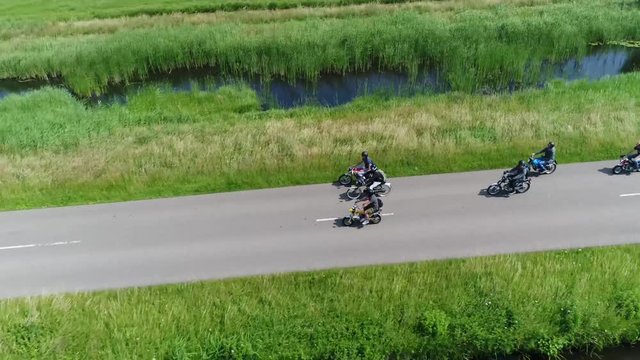 Aerial footage of mopeds driving over rural road close next to each other and overtaking each other a moped is small motorcycle generally having a less stringent licensing requirement than motorcycles