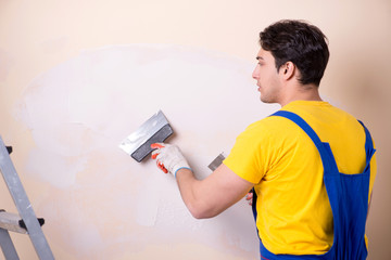 Young contractor employee applying plaster on wall