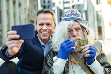 Happy help. Elderly office worker feeling extremely happy after helping street person begging for...