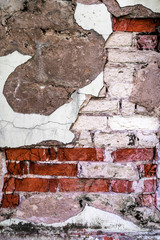 texture of a wall with destroyed bricks, crumbling plaster and damaged protective paint, abstract background