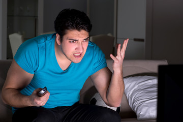 Young man watching football late at night