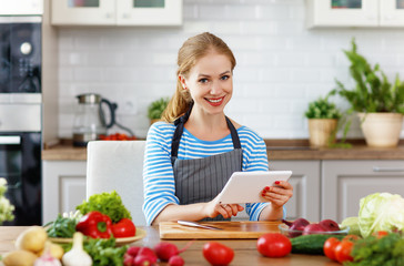happy woman preparing vegetables in kitchen on prescription with tablet
