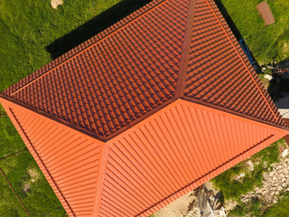House with an orange roof made of metal, top view. Metallic profile painted corrugated on the roof