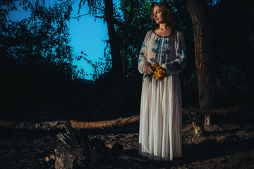 Woman in ethnic clothes near bonfire.