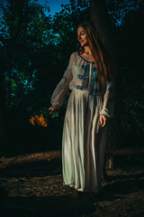 Woman in ethnic clothes dance in night forest
