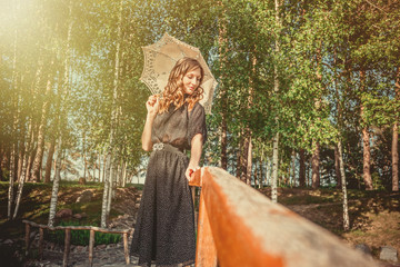 young woman hiding from the sun under white lace umbrella