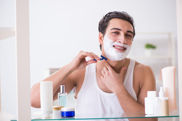 Young handsome man shaving early in the morning at home