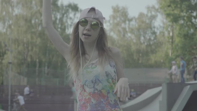 A young woman sits down at a park to listen to her favorite tunes, color profile Slog3