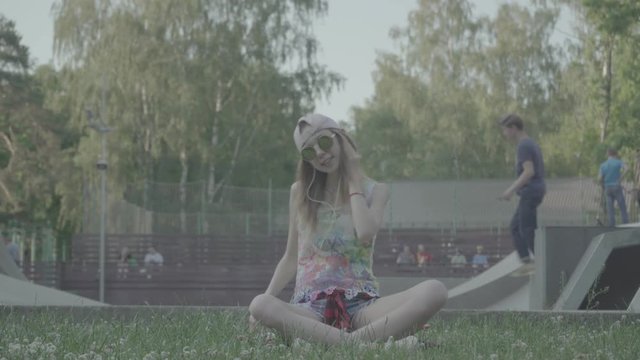 A young woman sits down at a park to listen to her favorite tunes, color profile Slog3