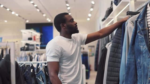 african american man chooses clothes hold sweater walk in store mall design business fashion shopping beauty black beautiful casual model style jeans portrait handsome slow motion