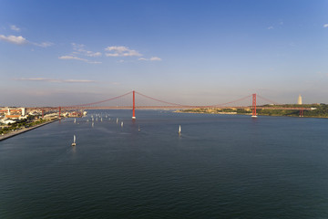 Aerial view of the city of Lisbon with sailboats on the Tagus River and the 25 of April Bridge on the background; Concept for travel in Portugal and visit Lisbon