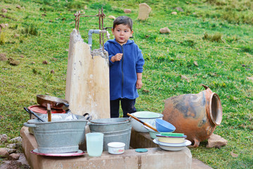 Little latin boy and a lot of dirty dishes in the countryside.
