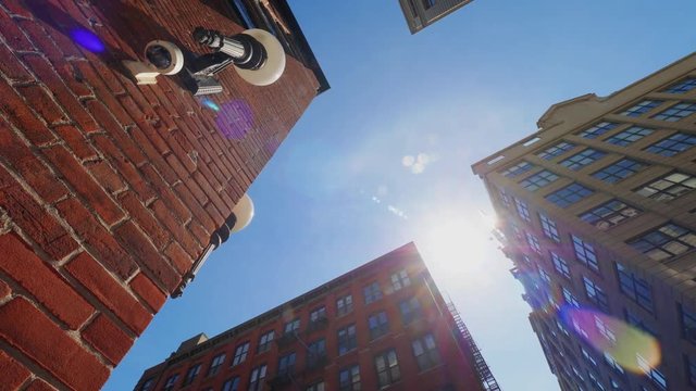 A low wide shot panning view looking up at red brick Brooklyn buildings. Shot at 60fps.  	