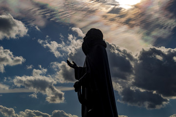 Silhouette of the Monument to the Monk Paphnutius Borowsky against the blue sky with clouds