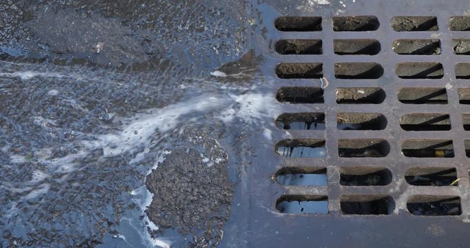 Closeup view of water running into a storm sewer on a Manhattan street.  	